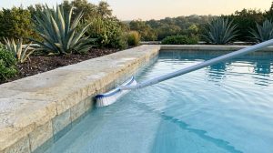 A pool brush cleaning the tile line of a swimming pool in Austin, Texas.